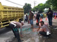 Personil polisi dan warga kecamatan Mayang, Jember, saat menembal jalanan yang berlubang jalur utama Jember - Banyuwangi.