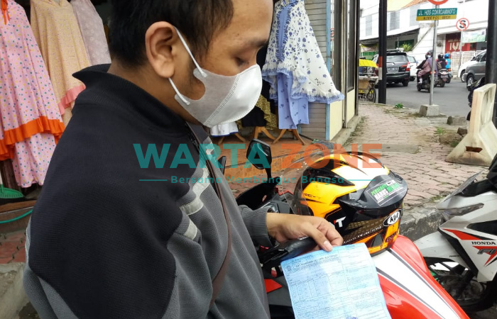 PASRAH: Salah satu pengendara motor saat menunjukkan surat tilang akibat memakai knalpot brong (Foto: Nur Imatus Safitri)
