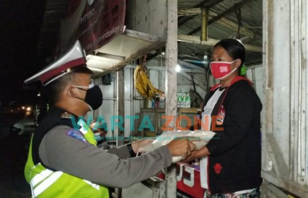 Caption: Anggota Satlantas Polres Jember saat membagikan sembako kepada PKL dan warga di sekitaran terminal Pakusari dan warga Desa Mrawan, Kecamatan Pakusari.