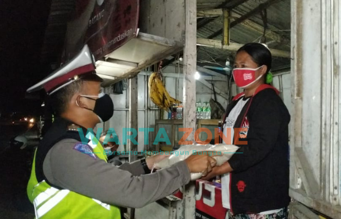 Caption: Anggota Satlantas Polres Jember saat membagikan sembako kepada PKL dan warga di sekitaran terminal Pakusari dan warga Desa Mrawan, Kecamatan Pakusari.
