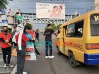 Caption: Sejumlah karyawan Erafone Jember saat membagikan nasi bungkus kepada pengendara yang melintasi di Jalan Gajahmada, Kecamatan Kaliwates, Jember.