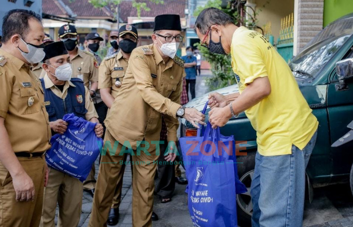 Caption: Bupati dan Wabup Jember, beserta Jajaran Forkopimda turun langsung untuk memberikan bantuan kepada warga yang terdampak Covid-19 di wilayah Perum Griya Mangli, Kecamatan Kaliwates (Foto: IG Pemkab Jember)