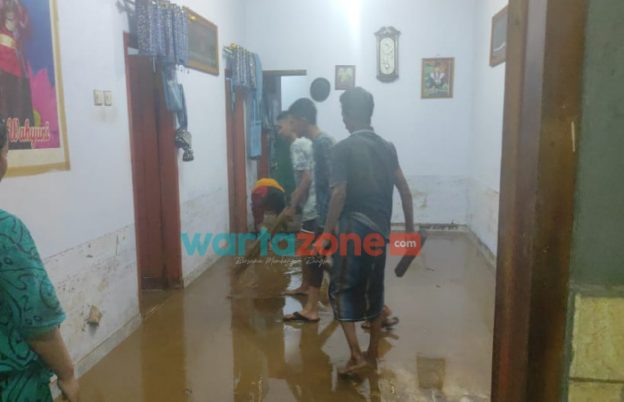 Caption: Tampak warga yang terdampak banjir saat melakukan pembersihan di dalam rumahnya, Kamis (18/11/2021) malam.