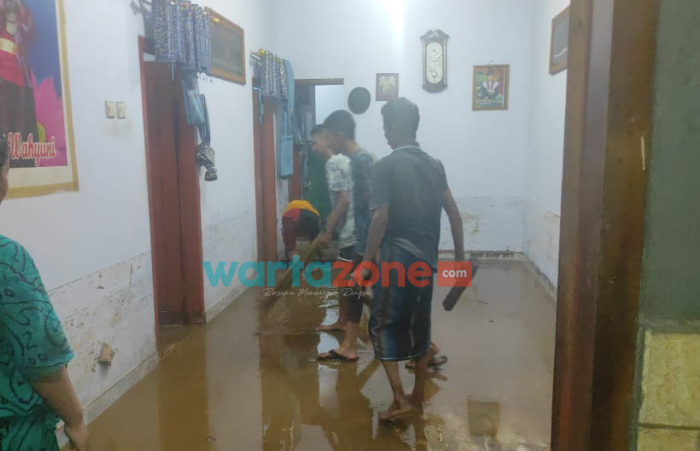 Caption: Tampak warga yang terdampak banjir saat melakukan pembersihan di dalam rumahnya, Kamis (18/11/2021) malam.