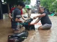 Foto: Sejumlah warga saat mengevakuasi motor yang sempat terbawa arus dan terkubur jalanan rusak akibat arus air banjir sangat deras, Minggu (9/1/2022).
