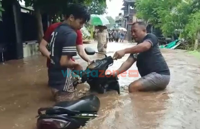 Foto: Sejumlah warga saat mengevakuasi motor yang sempat terbawa arus dan terkubur jalanan rusak akibat arus air banjir sangat deras, Minggu (9/1/2022).
