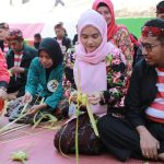 FOTO: Bupati Sumenep, H. Achmad Fauzi Wongsojudo bersama istri Hj. Nia Kurnia Fauzi saat membuat ketupat dalam Festival Ketupat 2025, di Pantai Slopeng Kecamatan Dasuk, Senin (7 April 2025).