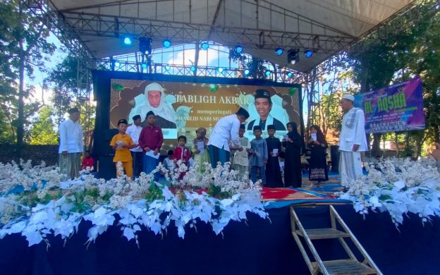 FOTO: Ketua Baznas Sumenep Ahmad Rahman, saat menyerahkan santunan anak yatim dalam gelaran Tabligh Akbar dan Pengajian Umum yang berlangsung di Lapangan Dusun Tengah, Desa Romben Guna, Minggu (20/07/2025).