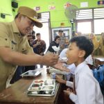 FOTO: Wakil Bupati (Wabup) Pamekasan H. Sukriyanto menyuapi salah satu siswa saat meninjau program Makan Bergizi Gratis (MBG) di SDN Laden 1, Senin (14/4/2025).