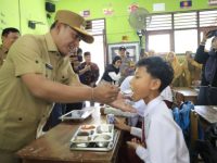 FOTO: Wakil Bupati (Wabup) Pamekasan H. Sukriyanto menyuapi salah satu siswa saat meninjau program Makan Bergizi Gratis (MBG) di SDN Laden 1, Senin (14/4/2025).